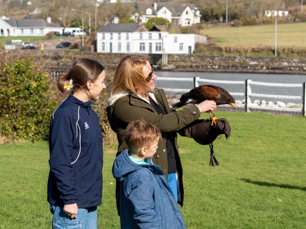 A mother petting a falcon in front of her children