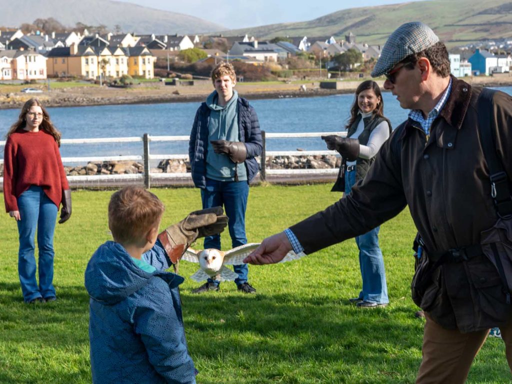 A falconer helping a young boy hold an owl